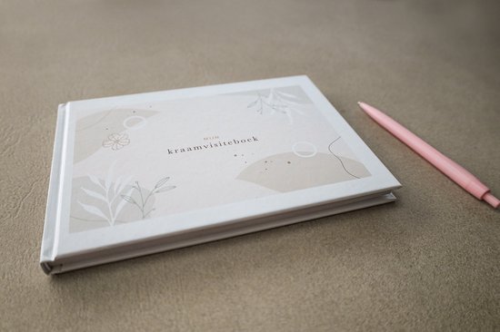 Een gesloten kraamvisiteboek met een licht beige omslag, versierd met abstracte vormen en botanische illustraties. Een roze pen ligt ernaast.