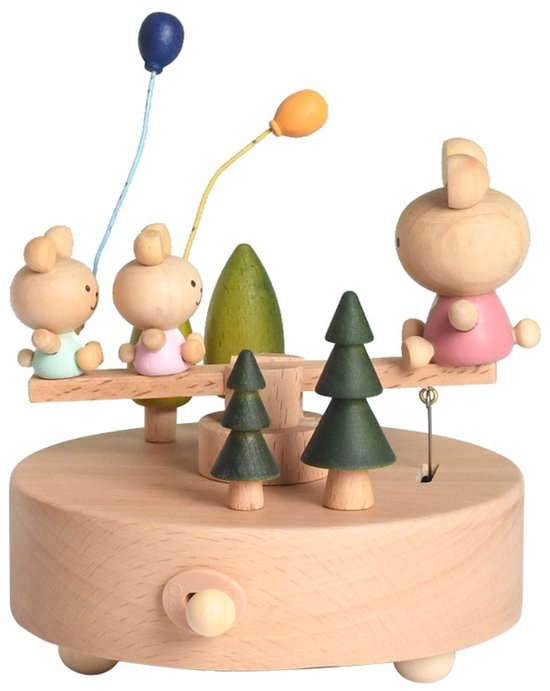 Houten muziekdoos met een wipwap waarop vier konijntjes zitten. Twee bomen en twee ballonnen completeren het tafereel.