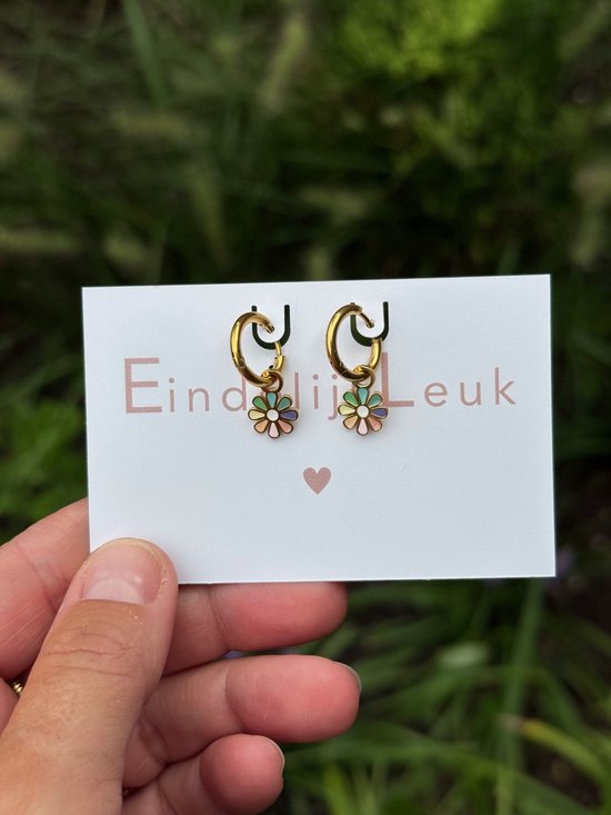 Twee gouden oorringetjes met geëmailleerde pastelkleurige bloemetjes, gepresenteerd op een kaart met 'Eindelijk Leuk'.