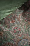 Detail van een groen dekbedovertrek met een rijke paisley print van bloemen en bladeren.