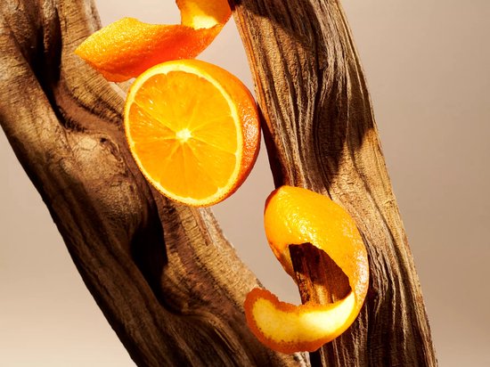 Een gesneden sinaasappel en sinaasappelschil tegen een houten achtergrond.