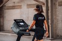 Vrouw met paardenstaart in zwart Focus Fitness shirt en zwarte broek loopt op een loopband.