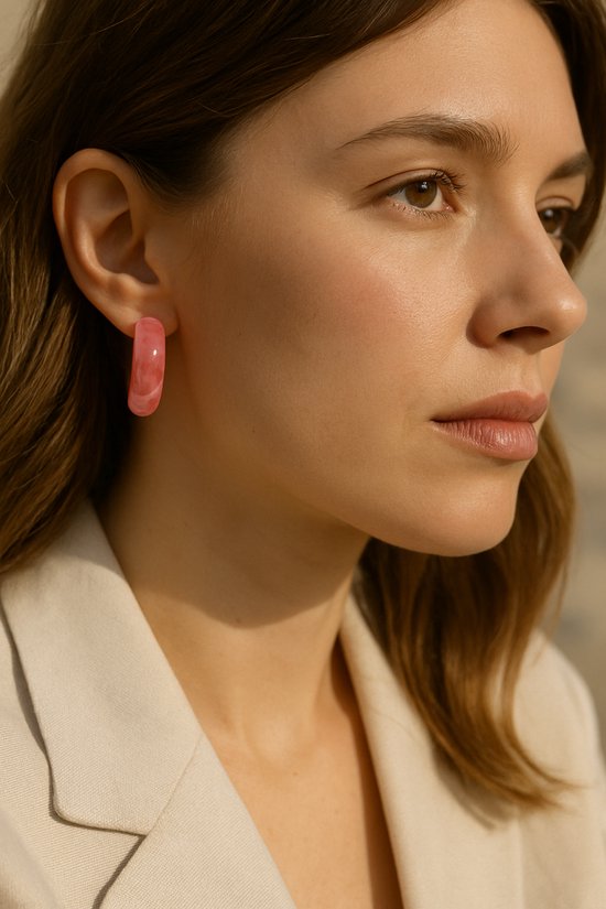 Roze acryl oorringen met een glanzende afwerking, gedragen door een model.