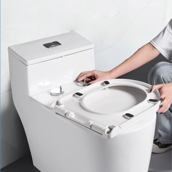 Een persoon bevestigt een wit toiletdeksel op een witte toiletpot met verchroomde scharnieren.