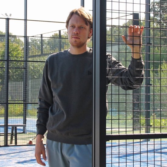 Man in charcoal Donnay fleece trui en grijze trainingsbroek op een sportveld.