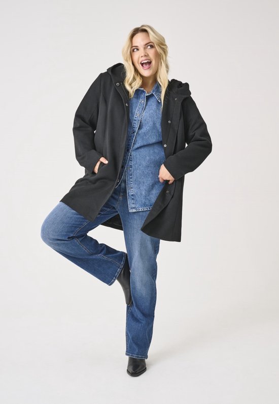 Model met zwart jack met capuchon, spijkerblouse en spijkerbroek.