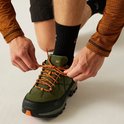Hommes nouant les lacets orange des chaussures de randonnée vertes.