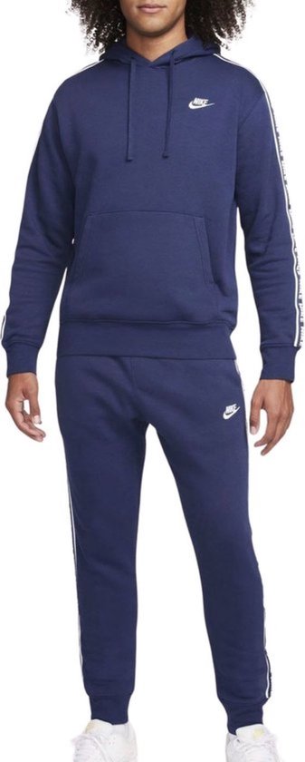 Donkerblauw Nike trainingspak met witte strepen op de mouwen en pijpen. Een capuchon met trekkoord en een buidelzak.