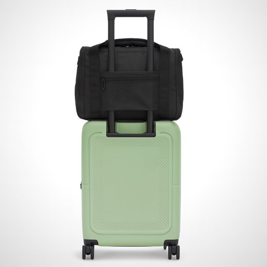 Zwarte BYMETZ weekendtas bovenop een lichtgroene koffer met wieltjes.