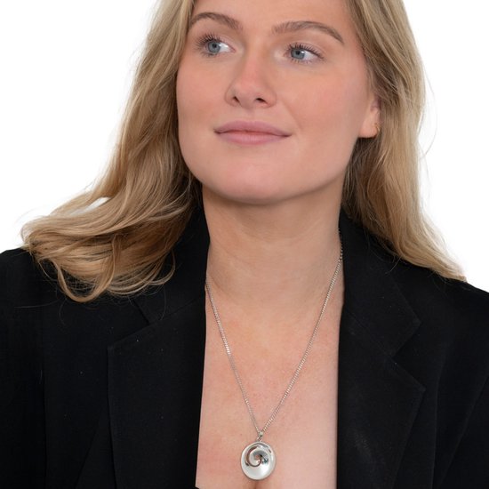 Blond model draagt een zilverkleurige schakelketting met een ronde hanger.