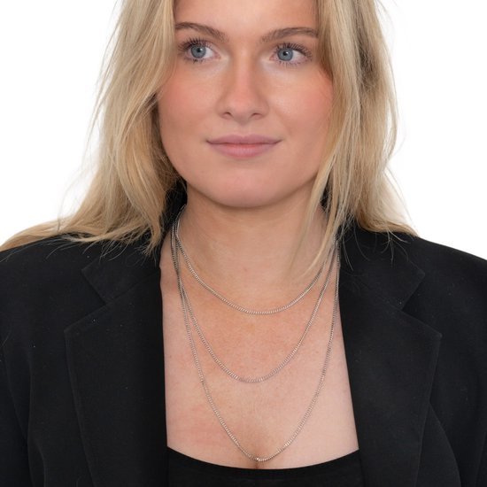 Blond model draagt een dunne zilverkleurige schakelketting van 3 lagen.