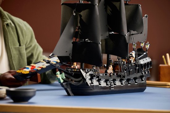 Homme avec le navire pirate LEGO du Capitaine Jack Sparrow, set 10365, par l'arrière.