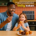 Vrolijke vader en dochter genieten van muffins, met de dubbele heteluchtfriteuse op de achtergrond.
