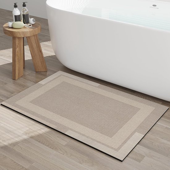Beige badmat met gedessineerd patroon naast een badkuip op een houten vloer.