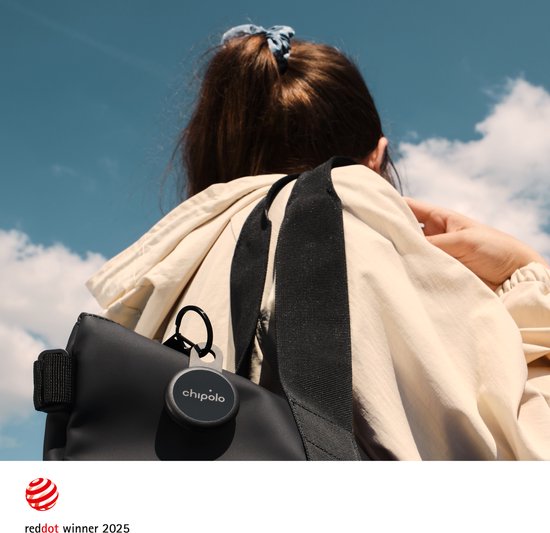 Vrouw draagt zwarte tas met Chipolo tracker eraan, op de achtergrond een blauwe lucht.