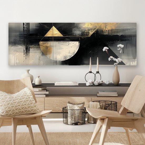 Abstract schilderij met geometrische vormen in zwart, wit en goud, hangend boven een dressoir met houten stoelen.