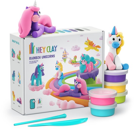 Hey Clay Rainbow Unicorns doos omringd door klei-eenhoorns, potjes klei en sculpturen. Een paarse eenhoorn ligt bovenop de doos.