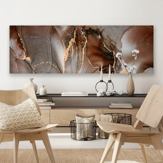 Abstract canvas met bruine, grijze en gouden marmerlook patronen, boven een houten dressoir.