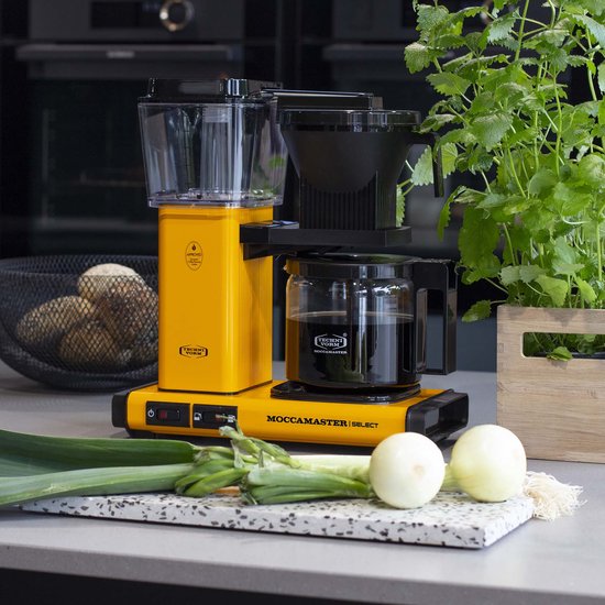 Felgeel Moccamaster koffiezetapparaat met glazen kan gevuld met koffie, op een aanrecht met groenten.