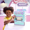 Jongen met gele gestreepte shirt met een paars-turquoise oven met een bruine pluche donut, die lacht naar de camera.