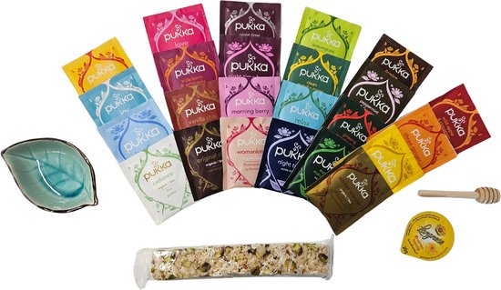 Een assortiment van Pukka theezakjes, een staafje honing, een keramieken blaadje en een reep met noten.