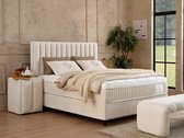 Gestoffeerd bed met een wit gestreept hoofdbord, een matras met sprei en kussens.