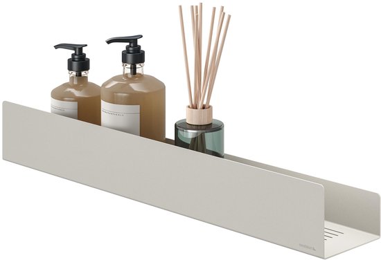 Een beige wandplank met twee bruine flacons en een diffuser met houten stokjes.