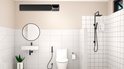 Zwarte infrarood heater gemonteerd boven een toilet in een moderne badkamer.