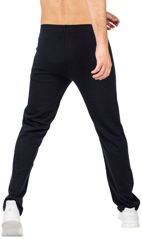 Zwarte joggingbroek met elastische tailleband en witte sneakers, gedragen door een man.
