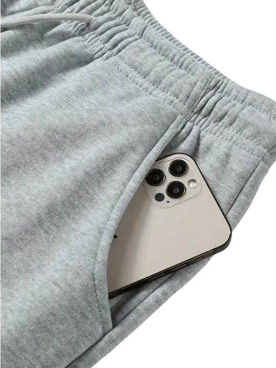 Een smartphone in de zak van een lichtgrijze joggingbroek.