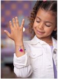 Meisje met krullend haar draagt een armband met roze hart en blauwe bedel. Ze kijkt lachwekkend naar de armband.