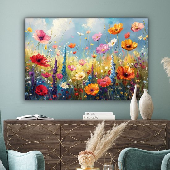 Une peinture d'un champ de fleurs avec des fleurs rouges, oranges et roses dans un salon avec un canapé beige et une table basse en bois.