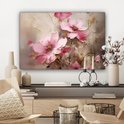 Canvas met roze bloemen, hangend boven een wandmeubel met decoratie.