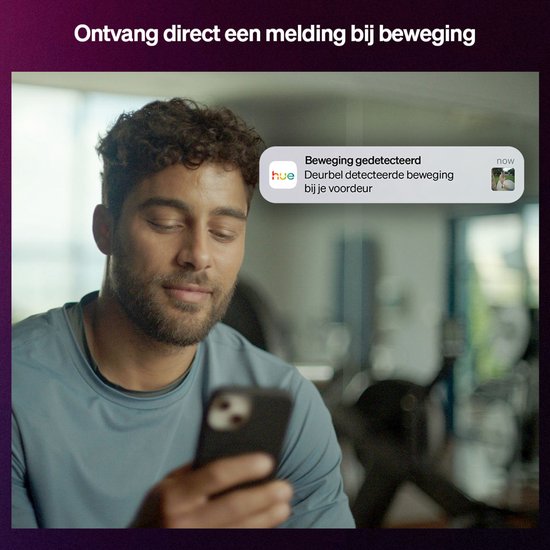 Man kijkt op zijn smartphone naar een melding 'Beweging gedetecteerd' van de Hue deurbel.