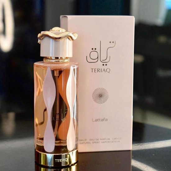 Roze parfumdoos en glazen fles met oranje vloeistof, witte accenten en gouden slang-dop.