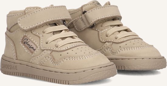 Close-up van twee taupe suède mid-top sneakers met klittenbandsluiting en veters.