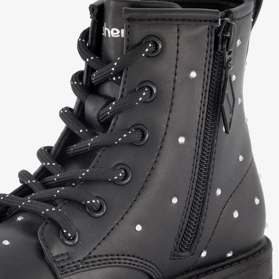 Detail van een zwarte Skechers laars met witte stippen en rits.