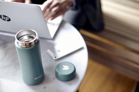 Een lichtgroene RETULP tumbler en deksel op een marmeren tafel, met een laptop.