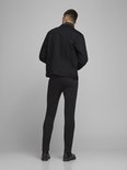 Achterkant van een man in zwarte skinny jeans en een zwarte spijkerjas.