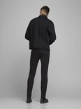 Achterkant van een man in zwarte skinny jeans en een zwarte spijkerjas.
