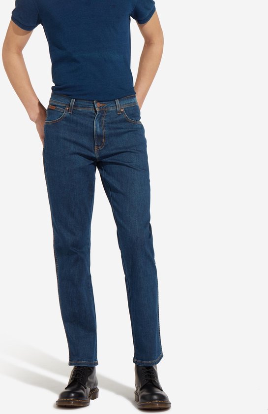 Blauwe Wrangler jeans, regular fit, gedragen met donkerblauw T-shirt en zwarte schoenen.
