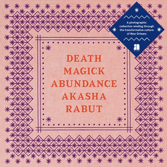 Boek met de titel 'DEATH MAGICK ABUNDANCE AKASHA RABUT' op een oranje achtergrond met paarse geborduurde rand.