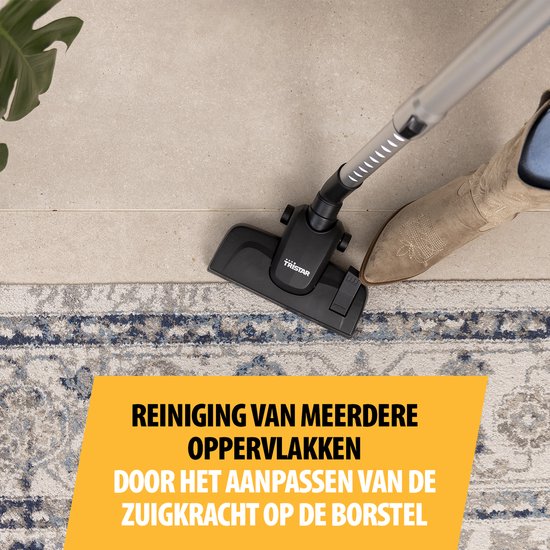 Close-up van een steelstofzuiger die een vloerkleed met blauwe patronen stofzuigt.