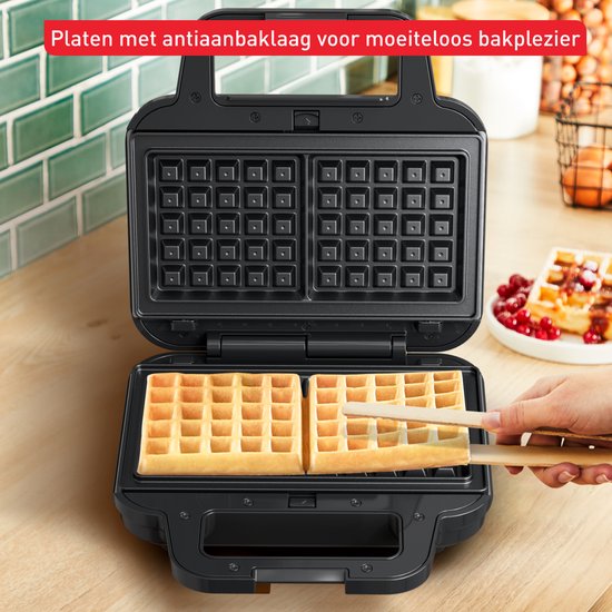 Open Tefal wafelijzer met twee goudbruine wafels, wordt met tangen uit het apparaat gehaald.