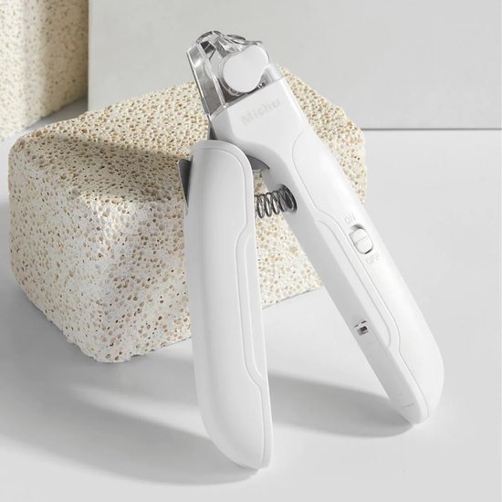 Witte PETKIT nagelknipper met LED-lichtje en schuurvijl, geplaatst op een poreuze steen.