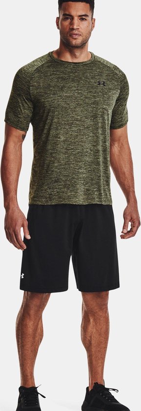 Man in olijfgroen gemêleerd Under Armour sportshirt en zwart sportbroekje.