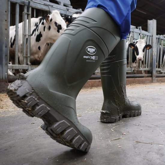 Groene Bekina werklaarzen met dik profiel, gedragen in een stal met koeien.