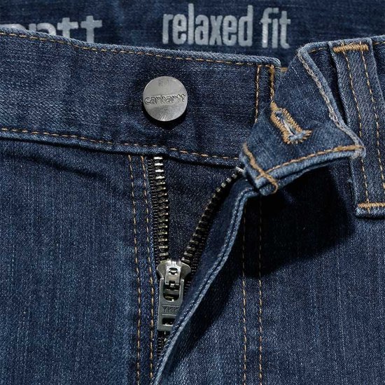 Detail van de ritssluiting en knoop van een Carhartt spijkerbroek.