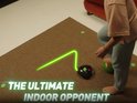 Een meisje speelt met de SoccerBot en Smart Ball, met een groene lichtbaan op de vloer. Tekst: 'The Ultimate Indoor Opponent'.