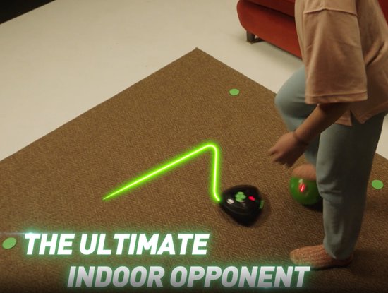 Een meisje speelt met de SoccerBot en Smart Ball, met een groene lichtbaan op de vloer. Tekst: 'The Ultimate Indoor Opponent'.
